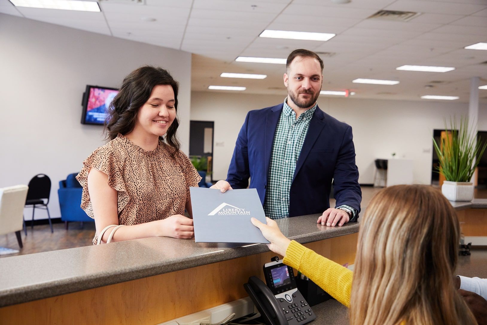 A man and a woman at the Liberty Mountain Conference Center desk receiving assistance from an on-site staff member